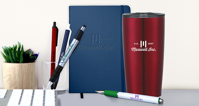 Promotional pens, custom notebook, stainless steel tumbler, assorted office promotional products with logos on a desk